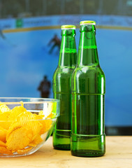 Beer and chips in front of TV with hockey match.