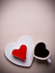 Heart shaped coffee cup and cake on wood surface