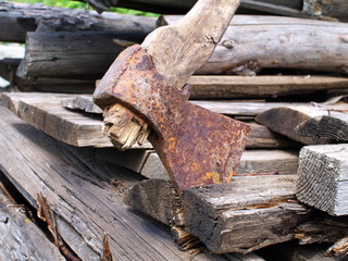 Used rusty axe with rotten haft on old wooden boards, closeup, shallow depth of field