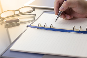 Blank note paper with pen, digital table and glasses. Theme business meeting concept. Warm tone.