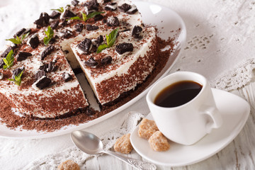 Cheese cake with pieces of chocolate cookies and coffee close-up. horizontal
