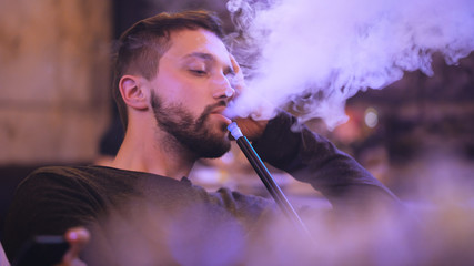 handsome man smokes hookah in the bar