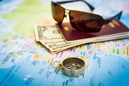 Compass, passport, money and sunglasses on the map
