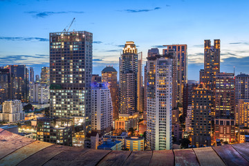 Obraz na płótnie Canvas night light of Bangkok wooden floor. Panoramic and perspective view background of glass high rise building skyscraper commercial of future. Business concept of success industry tech architecture