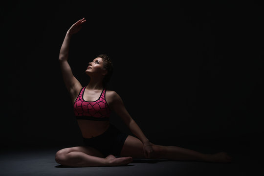 Studio photo of graceful woman exercising in dark