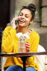 Cheerful african lady using mobile phone at outdoor cafe