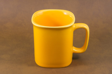 Obraz premium yellow mug with brown background