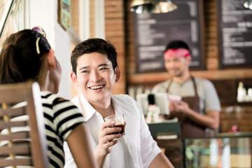Asian couple in cafe flirting while drinking coffee