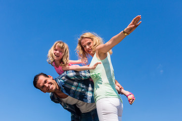 Vater, Mutter, Tochter spielen Flieger, leichte Untersicht