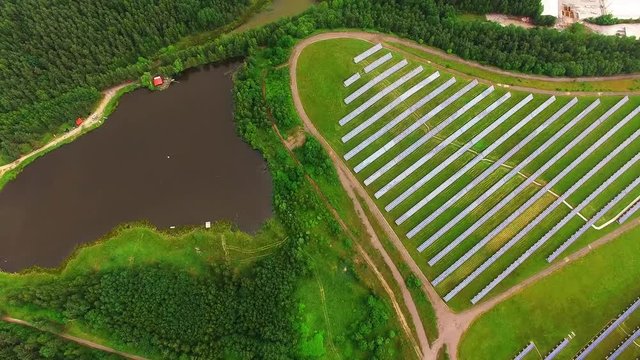 Camera flight over a solar power plant in agricultural landscape. Industrial background on renewable resources theme. Industry of power and fuel generation in European Union.