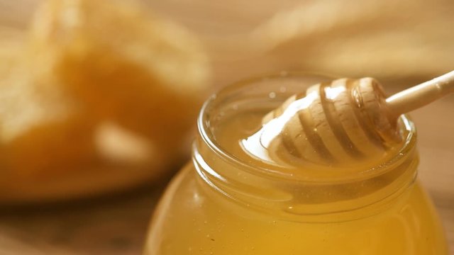 Honey in jar with honey dipper on wooden background