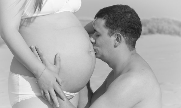 Happy father kissing pregnant belly,Happy father kissing pregnant woman's belly,black and white photo