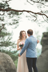 Gorgeous bride, groom kissing and hugging near the cliffs with stunning views