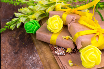 Yellow gift box wrapped in natural paper on wooden table top view

