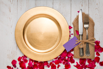 Silverware with an empty tag on a table with an gold plate