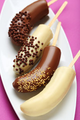 Banana covered in chocolate on a pink background