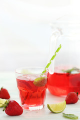 Fresh strawberry drink in glass with lime on wooden table