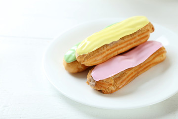 Eclairs with glaze on a white wooden table