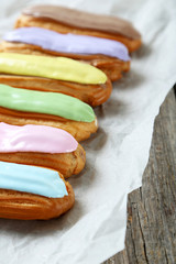 Eclairs with glaze on a grey wooden table