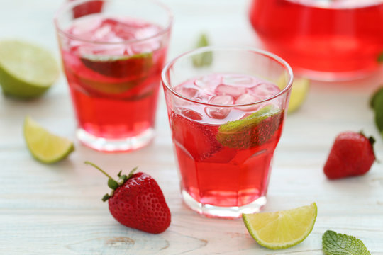 Fresh strawberry drink in glass with lime on wooden table