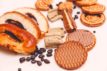 There are Pieces of  Roll with poppyseed,Cookies,Halavah,Chocolate Peas,Tasty Sweet Food on the White Background