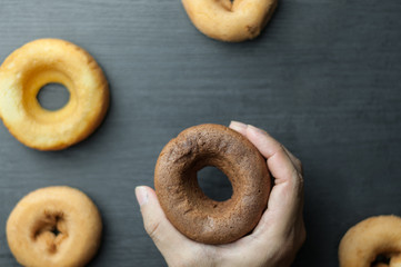  hand holding donut over donuts.