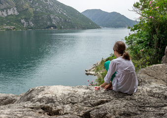 Fototapeta na wymiar Девочка смотрит на панораму залива с побережья, Черногория