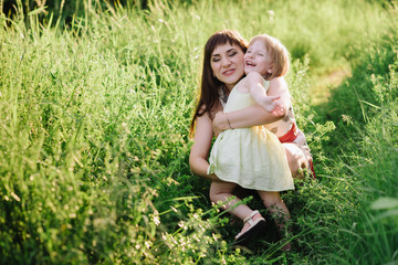 Mom kisses and hugs daughter on nature, family, motherhood, child