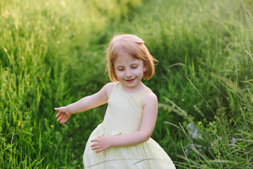 Fototapeta na wymiar Outdoor portrait of a cute little girl playing in the grass, childhood, happiness, nature, relaxation