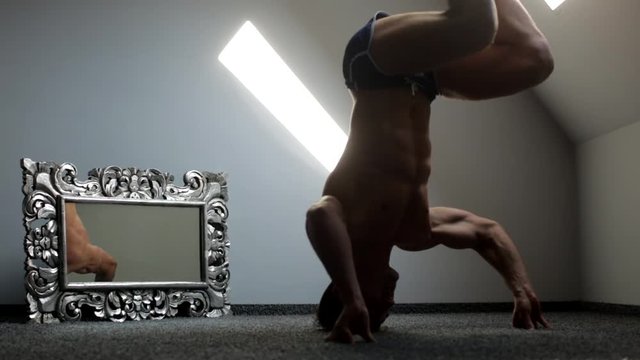 A brawny boy making headstand and exercises with legs