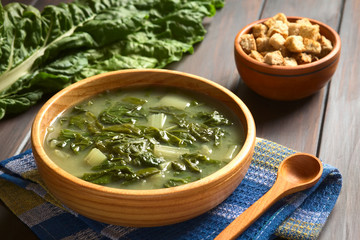Mangoldsuppe mit Croutons im Hintergrund, fotografiert mit natürlichem Licht (Selektiver Fokus, Fokus ein Drittel in die Suppe)