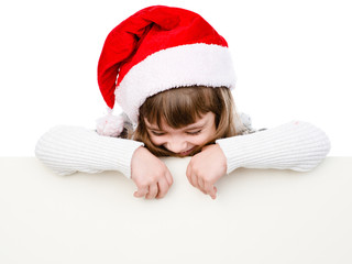 Happy Christmas girl with santa hat behind white board looking d