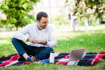 Young and attractive man relaxes in the park at lunch time