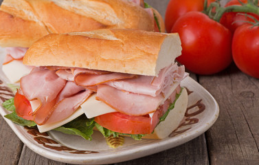 Ham Sub Sandwich Closeup With Tomatoes in Background