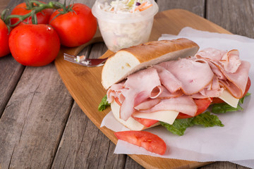 Ham and Cheese Sub Sandwich With Tomatoes and Coleslaw in Background © chas53