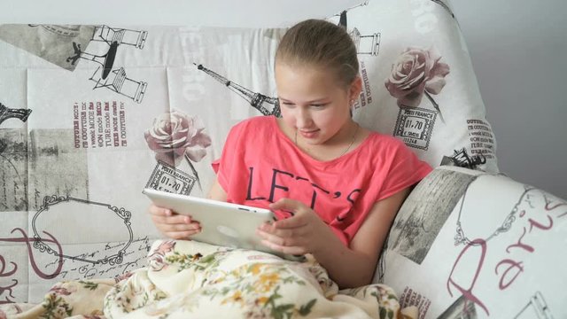 Child lying on the bed with a digital tablet