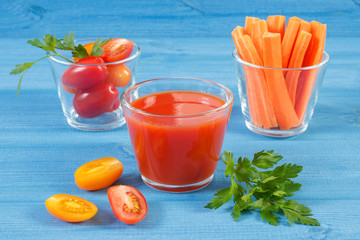 Tomato juice and vegetables on blue board, healthy nutrition