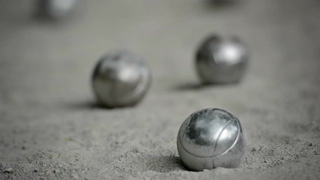 Video 1080p FullHD - Selective focus shifting from front to back of Petanque balls on a coarse, sandy play area in Laos.