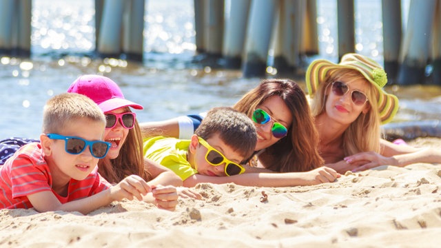 Happy family women kids sunbathing on beach.