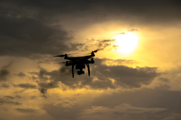 Flying drone with camera on the sky at sunset
