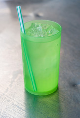 the green drinking straw in a green plastic grass of ice water i