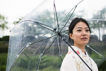 Young attractive Japanese woman in kimono holding an umbrella on a rainy day