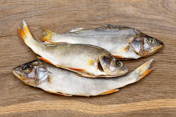 Three dried fishes on a vintage wooden bacground.