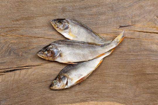 Three dried fishes on wooden background.