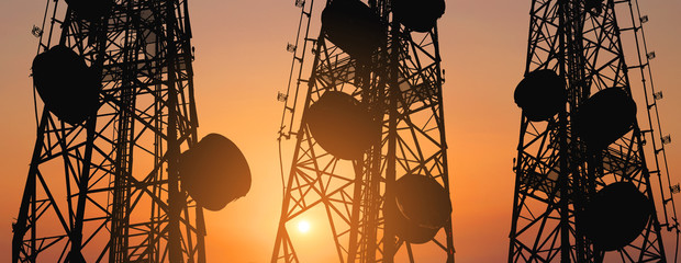 Silhouette, telecommunication towers with TV antennas and satellite dish in sunset, panorama...