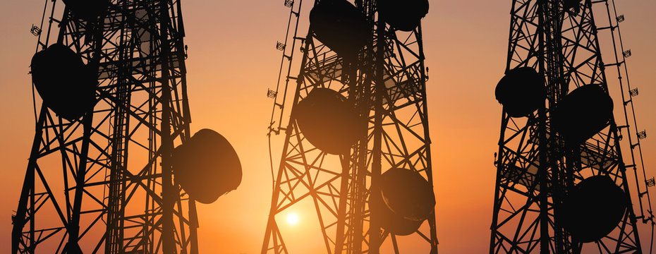 Silhouette, telecommunication towers with TV antennas and satellite dish in sunset, panorama composition
