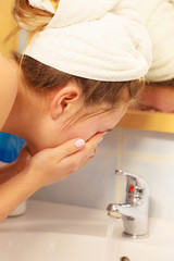 Woman washing face in bathroom. Hygiene