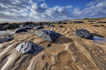 Fototapeta na wymiar Ireland, Fanore beach with intensive orange sand and black scattered rocks, nature