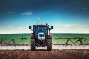 Farming tractor plowing and spraying on field