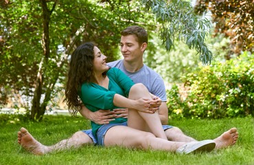Fototapeta premium Romantic couple sit on grass in city park, summer season, lovers boy and girl